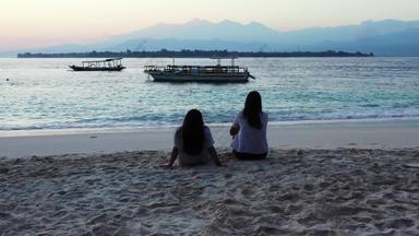 年轻的快乐女士们拍的太阳海滩清洁白色沙子蓝色的背景